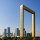 Golden Frame monument with Dubai skyline and modern skyscrapers in background under clear blue sky
